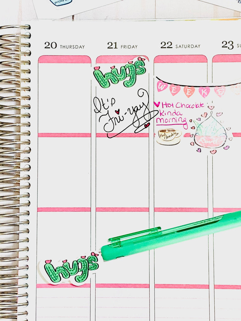 A planner with a Cactus Valentin Sticker that says "Hugs". It's Fri-Yay" is written in the planner along with other Valentine's Day stickers.